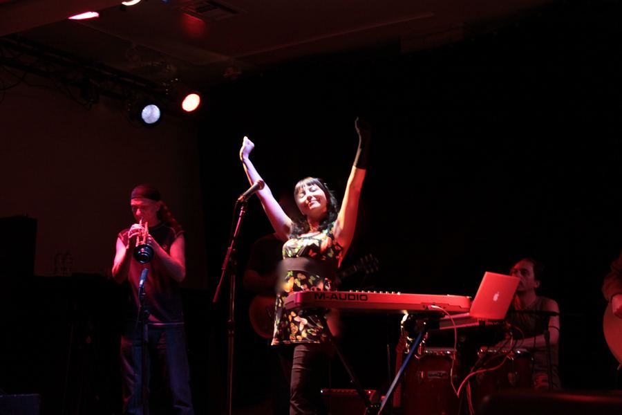 Sol Aravena singing live, arms raised