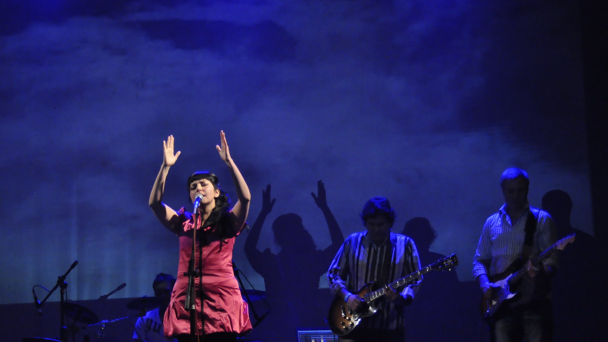 Sol Aravena performing on stage, arms raised
