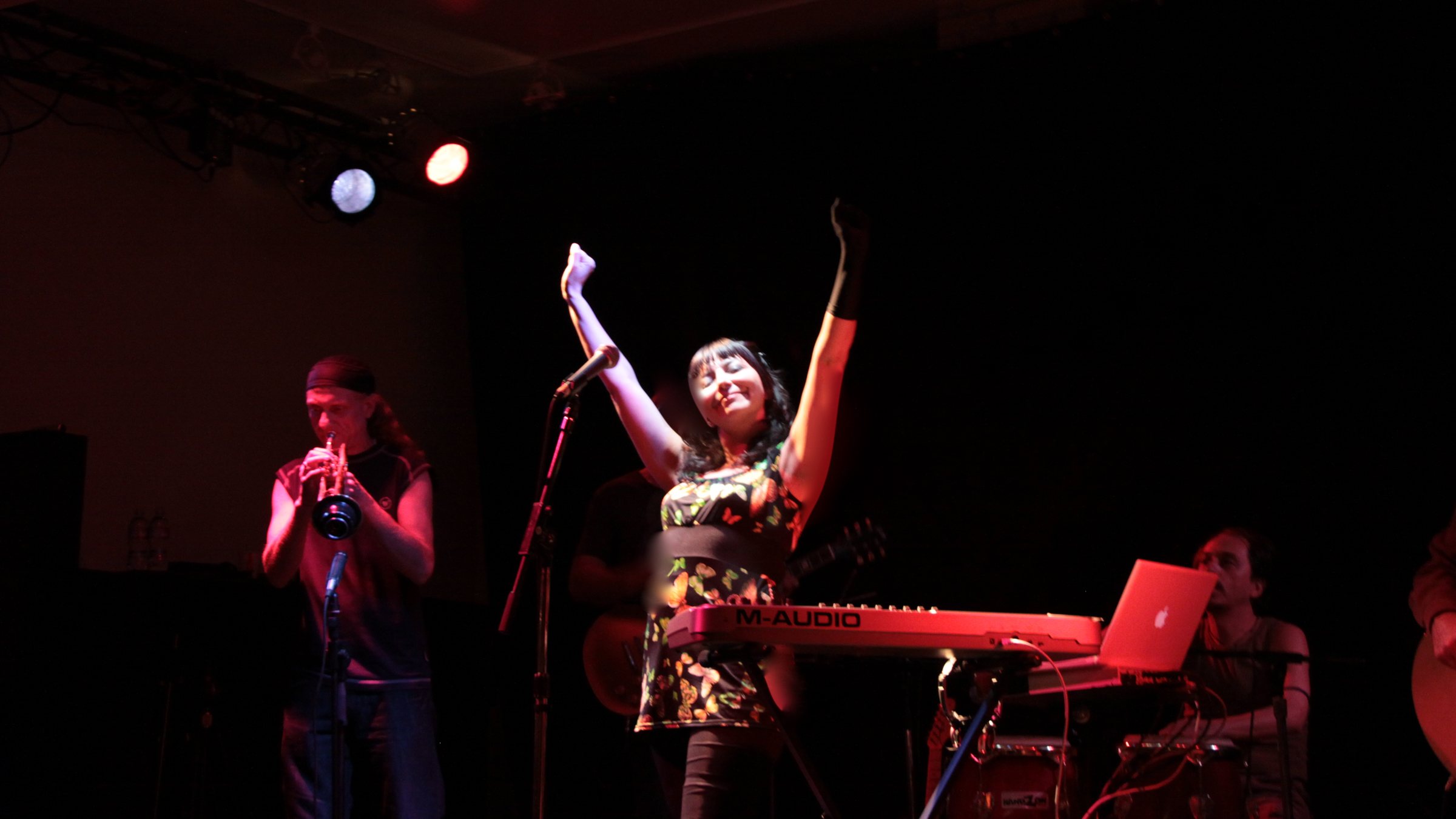 Sol Aravena singing live under red stage light
